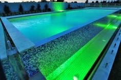 Backyard swimming pool lit with blue LED lighting at dusk